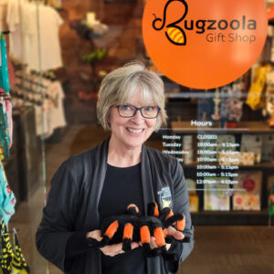 Photo of Kate in front of the Bugzoola Gift Shop holding a stuffed toy tarantula.